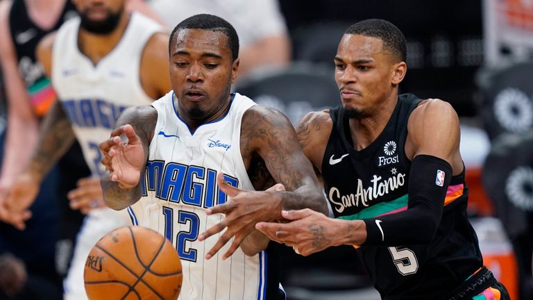 Orlando Magic forward Gary Clark (12) and San Antonio Spurs guard Dejounte Murray (5) scramble for the ball during the second half of an NBA basketball game in San Antonio, Friday, March 12, 2021.