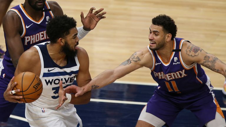 Minnesota Timberwolves's Karl-Anthony Towns (32) tries to maintain control of the ball against Phoenix Suns' Abdel Nader (11) in the first half of an NBA basketball game Sunday, Feb. 28, 2021, in Minneapolis.
