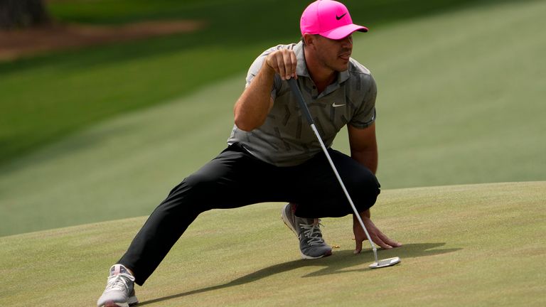 Brooks Koepka stretches to line up a putt on the 14th green during the first round of the Masters                  