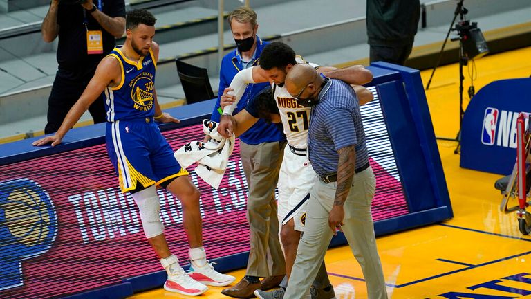 AP - Golden State Warriors' Stephen Curry, left, watches as Denver Nuggets guard Jamal Murray (27) is helped off the floor