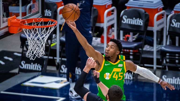 Utah Jazz guard Donovan Mitchell lays the ball up while guarded by Portland Trail Blazers center Jusuf Nurkic