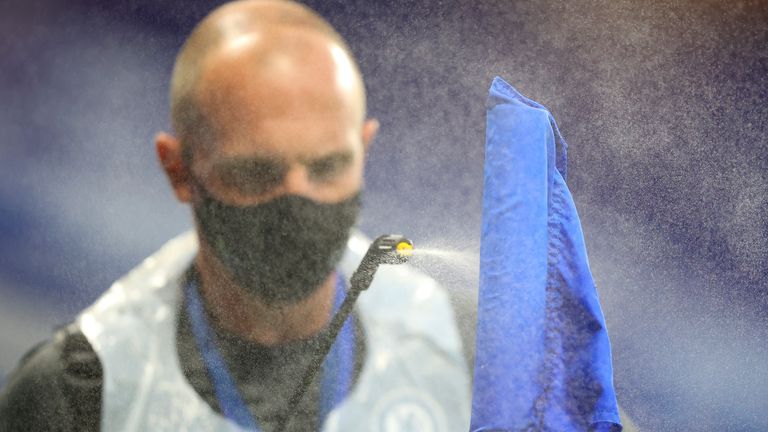 A groundsman sprays disinfectant on a corner flag during the English Premier League soccer match between Chelsea and Norwich City 