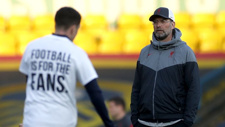 Liverpool manager Jurgen Klopp looks on as a Leeds United player warms up on the pitch wearing a shirt opposing the new European Super League