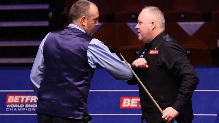 Mark Williams (L) of Wales interacts with John Higgins of Scotland following the Betfred World Snooker Championship Round Two match between Mark Williams of Wales and John Higgins of Scotland at Crucible Theatre on April 24, 2021 in Sheffield, England. A maximum of 50% of the venue capacity is allowed to open for spectators as part of a Government pilot event. (Photo by George Wood/Getty Images)