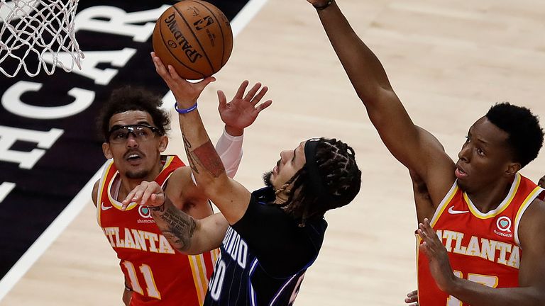 Orlando Magic guard Cole Anthony, center, shoots against Atlanta Hawks&#39; Trae Young (11) and Onyeka Okongwu (17) in the first half of an NBA basketball game Tuesday, April 20, 2021, in Atlanta.