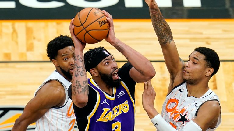 Los Angeles Lakers forward Anthony Davis (3) takes shot as he gets between Orlando Magic guard Chasson Randle, left, and forward Chuma Okeke (3)during the first half of an NBA basketball game, Monday, April 26, 2021, in Orlando, Fla. 