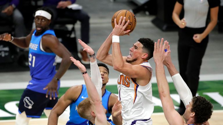 Phoenix Suns' Devin Booker, center, drives to the basket against multiple Milwaukee Bucks defenders during the second half of an NBA basketball game Monday, April 19, 2021, in Milwaukee. (AP Photo/Aaron Gash) 