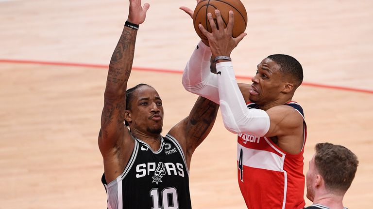 Washington Wizards guard Russell Westbrook, center, goes to the basket against San Antonio Spurs forward DeMar DeRozan, left, and center Jakob Poeltl, right, during the second half of an NBA basketball game, Monday, April 26, 2021, in Washington.