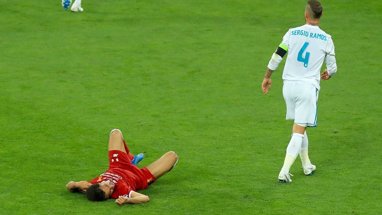 لاعب ليفربول محمد صلاح (يسار) مستلقي على أرض الملعب بعد مواجهة من ريال مدريد سيرجيو راموس خلال نهائي دوري أبطال أوروبا.