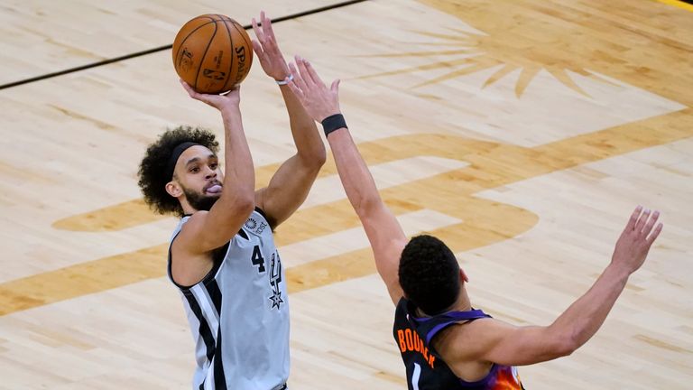 San Antonio Spurs guard Derrick White shoots over Phoenix Suns guard Devin Booker (1) during the first half of an NBA basketball game Saturday, April 17, 2021, in Phoenix. (AP Photo/Rick Scuteri)


