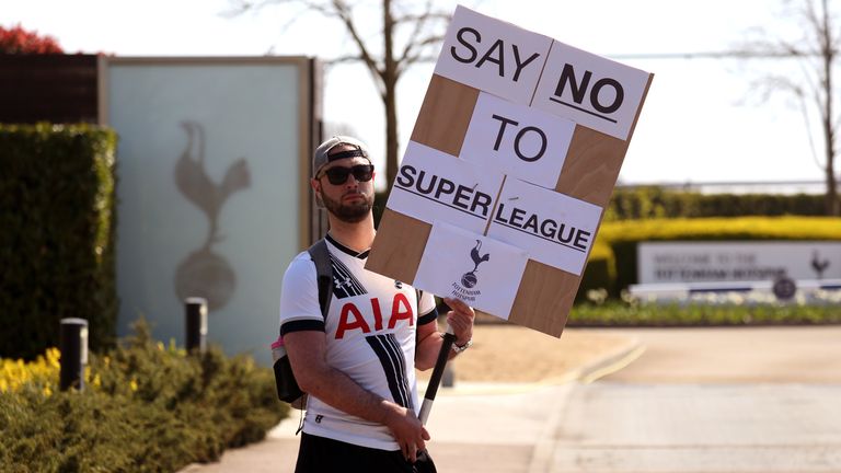 A Spurs fan holding a placard outside the club's training facility in protest against plans for a European Super League