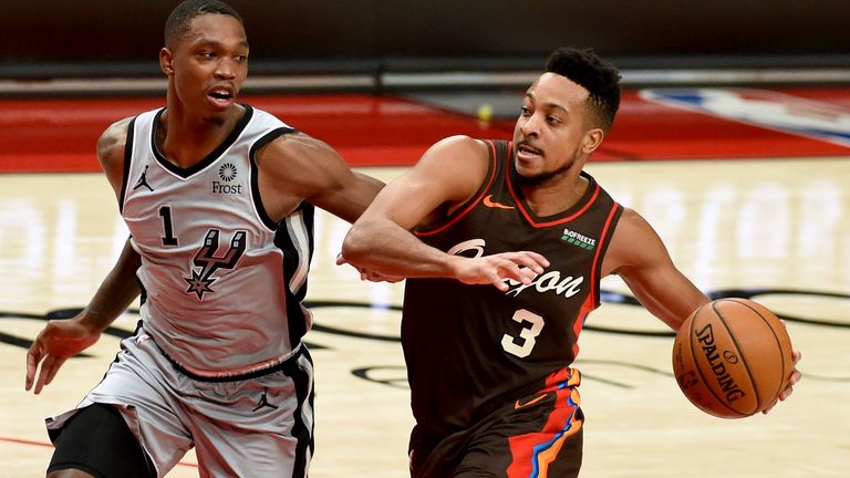 Portland Trail Blazers guard CJ McCollum, right, drives to the basket on San Antonio Spurs guard Lonnie Walker IV, left, during the second half of an NBA basketball game in Portland, Ore., Saturday, May 8, 2021. The Blazers won 124-102. (AP Photo/Steve Dykes)..