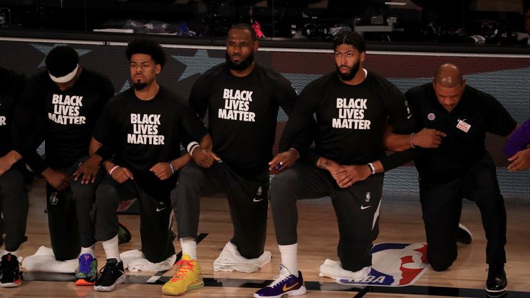 Los Angeles Lakers&#39; LeBron James, third from left, and Anthony Davis, second from right, wear Black Lives Matter shirts as they kneel with teammates during the national anthem prior to an NBA basketball game against the Los Angeles Clippers, Thursday, July 30, 2020, in Lake Buena Vista, Fla.