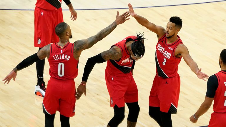 Portland Trail Blazers guard Damian Lillard high fives guard CJ McCollum over  forward Robert Covington during the second half of an NBA basketball game against the Phoenix Suns