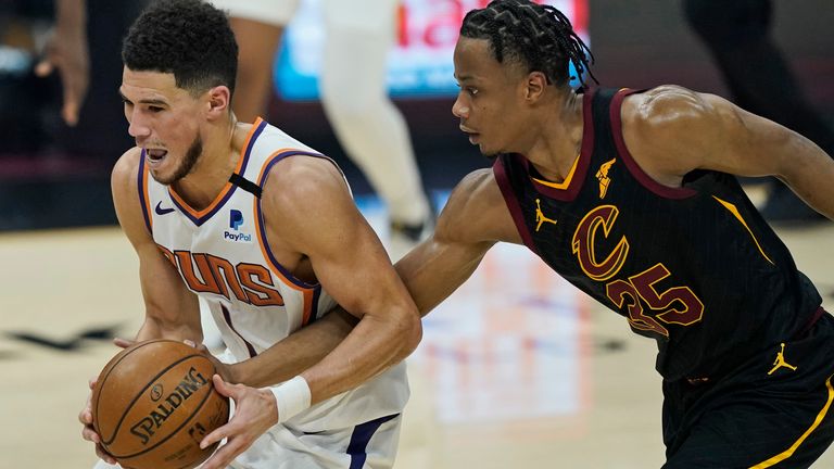 Phoenix Suns' Devin Booker, left, drives past Cleveland Cavaliers' Isaac Okoro in the first half of an NBA basketball game, Tuesday, May 4, 2021, in Cleveland.