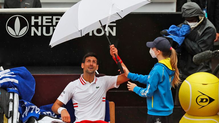 Novak Djokovic of Serbia holds an umbrella during a pause of his match against Taylor Fritz of the United States at the Italian Open tennis tournament, in Rome, Tuesday, May 11, 2021. (AP Photo/Alessandra Tarantino)