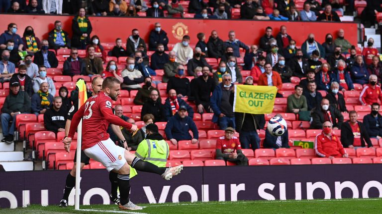 A Manchester United supported hold up a &#39;Glazers Out&#39; flag behind Shaw as he takes a corner