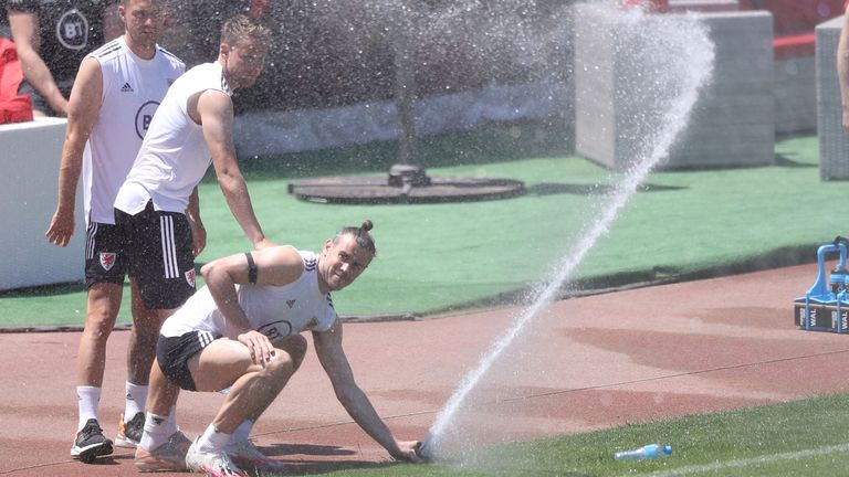 Gareth Bale fiddles with the sprinkler in the soaring heat in Baku during training