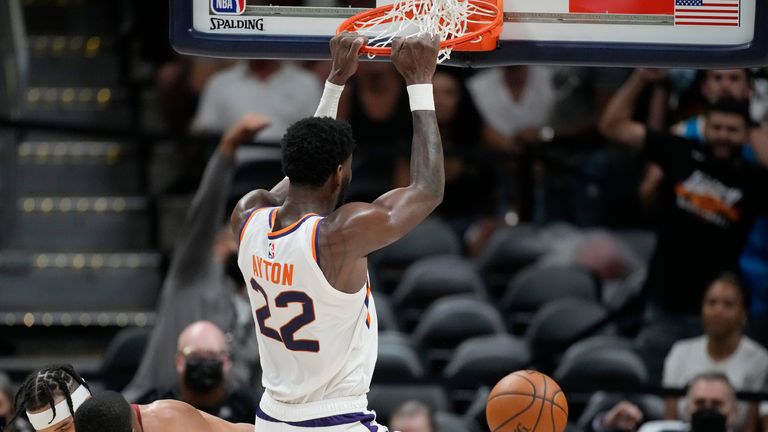 Phoenix Suns center Deandre Ayton, right, hangs from the rim after dunking the ball as Denver Nuggets forward Will Barton, front left, and center JaVale McGee defend in the second half of Game 4 of an NBA second-round playoff series, Sunday, June 13, 2021, in Denver. Phoenix won 125-118 to sweep the series. 