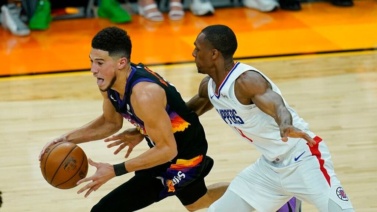 Phoenix Suns guard Devin Booker, left, drives past Los Angeles Clippers guard Rajon Rondo during the first half of Game 1 of the NBA basketball Western Conference finals Sunday, June 20, 2021, in Phoenix. The Suns defeated the Clippers 120-114. (AP Photo/Ross D. Franklin)