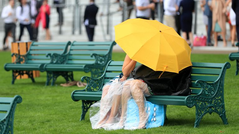 Racegoers shelter from rain at Royal Ascot on Thursday