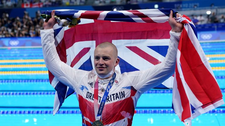 Great Britain's Adam Peaty poses with his gold medal on the podium after winning the Men's 100m Breaststroke final at the Tokyo Aquatics Centre