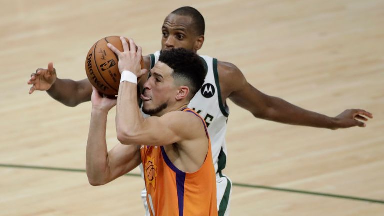 Phoenix Suns guard Devin Booker drives to the basket ahead of Milwaukee Bucks forward Khris Middleton during Game 4 of basketball&#39;s NBA Finals