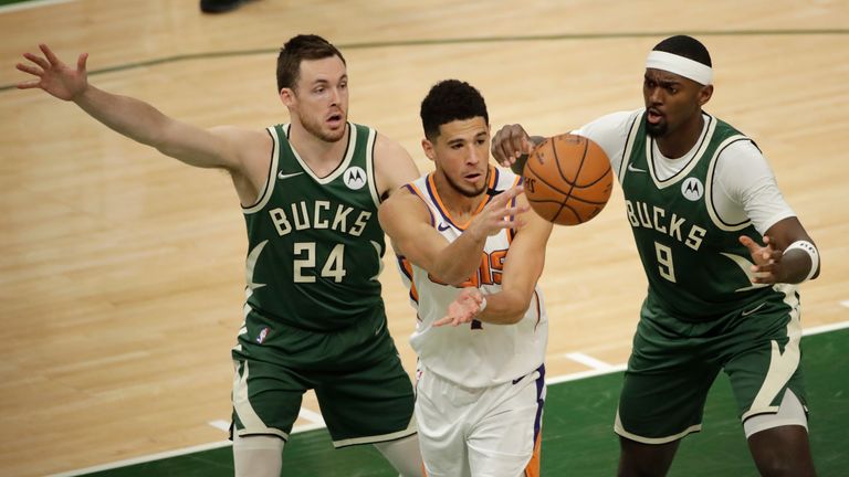 Phoenix Suns&#39; Devin Booker passes the ball between Milwaukee Bucks&#39; Pat Connaughton (24) and Bobby Portis (9) during the first half of Game 3 of basketball&#39;s NBA Finals Sunday, July 11, 2021, in Milwaukee. (AP Photo/Aaron Gash)