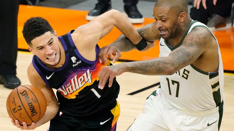 Phoenix Suns guard Devin Booker, left, is defended by Milwaukee Bucks forward P.J. Tucker during the first half of Game 5 of basketball&#39;s NBA Finals, Saturday, July 17, 2021, in Phoenix.
