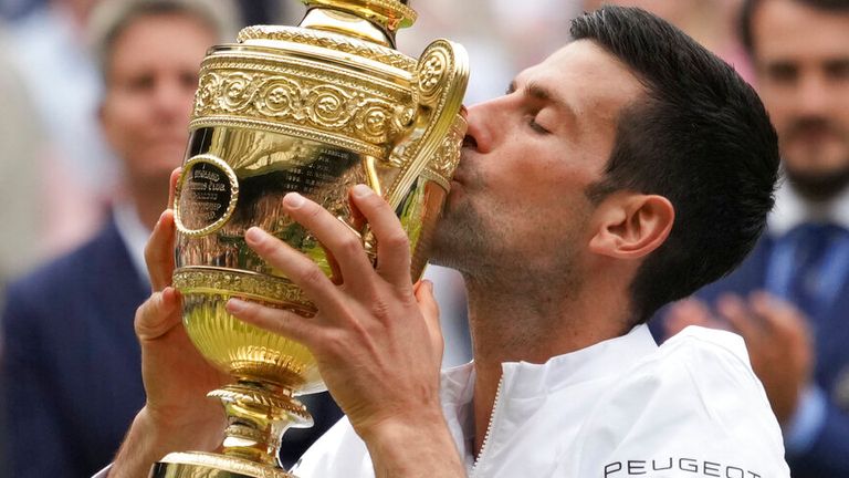 Serbia's Novak Djokovic kisses his winner's trophy and celebrates his victory over Italy's Matteo Berrettini during the men's singles final match on day thirteen of the Wimbledon Tennis Championships in London, Sunday, July 11, 2021. (AP Photo/Alberto Pezzali)