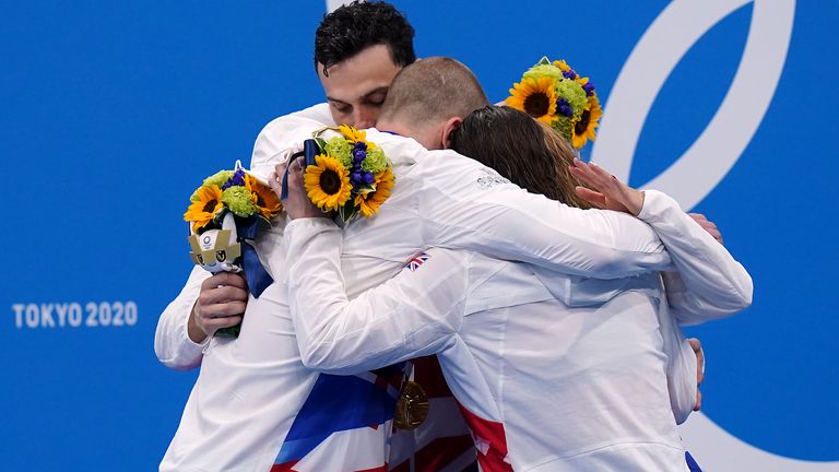 The 4x100m medley team embrace eachother after claiming gold