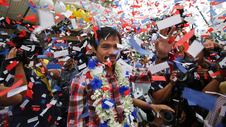 Filipino boxing hero Manny Pacquiao waves as confetti falls during a heroes welcome at the financial district of Makati, south of Manila, Philippines on Thursday Nov. 27, 2014. Pacquiao recently defeated Chris Algieri of the United States to win the WBO world welterweight title. (AP Photo/Aaron Favila)