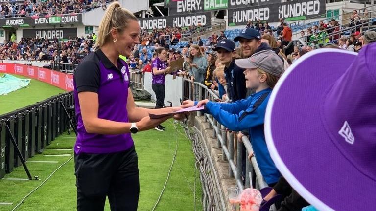 Phoebe signs an autograph for a young fan during The Hundred