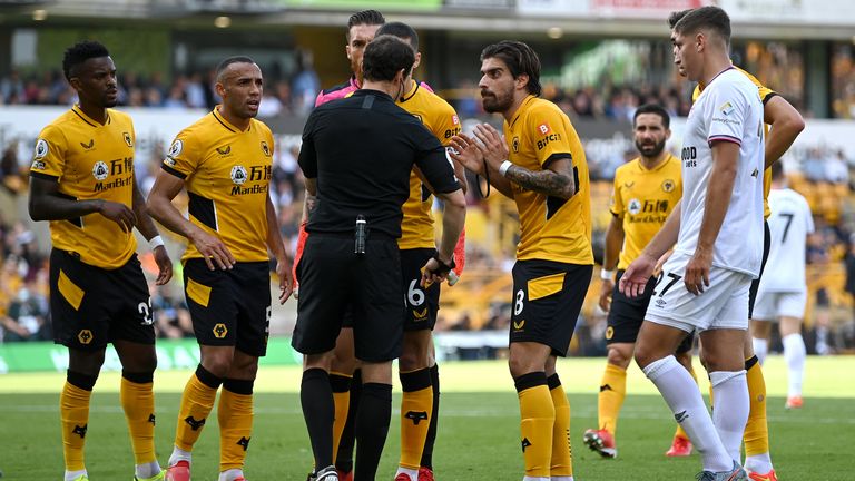 Conor Coady,  Ruben Neves and their Wolves teammates surround referee Darren England in protest at the penalty to Brentford