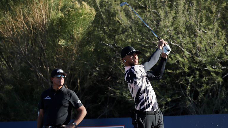 Stephen Curry plays his shot from the ninth tee as Phil Mickelson looks on during The Match: Champions For Change at Stone Canyon Golf Club