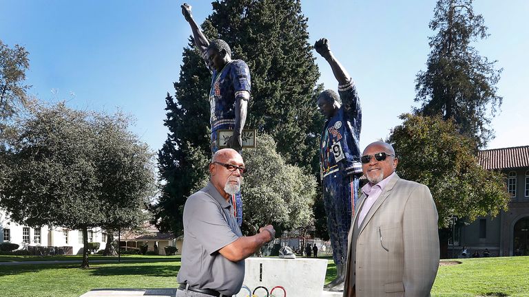 Carlos and Smith in front of a statue that honours their iconic protest on the campus of San Jose State University in 2018