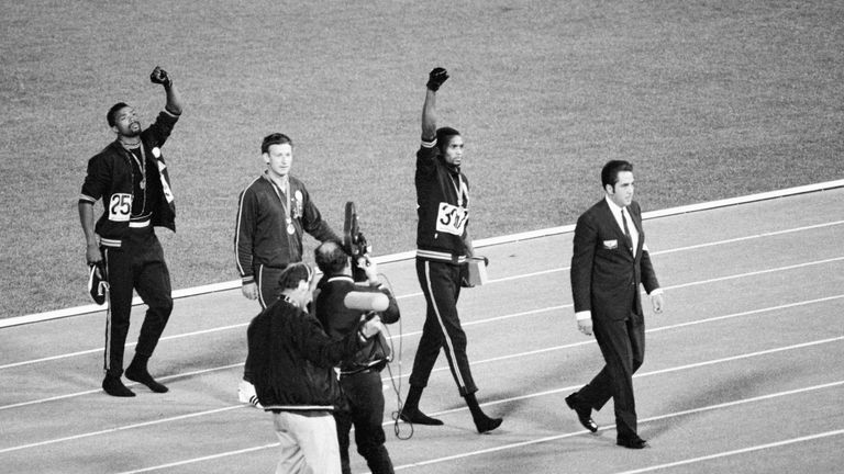 Smith (centre) and Carlos (right) continue with their raised gloved hands after they walk off the podium in 1968