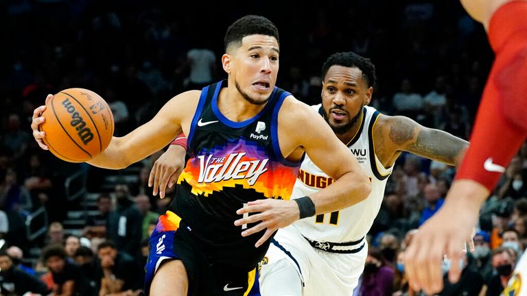 Phoenix Suns guard Devin Booker drives as Denver Nuggets guard Monte Morris, right, pursues during the second half of an NBA basketball game, Wednesday, Oct. 20, 2021, in Phoenix. (AP Photo/Matt York)