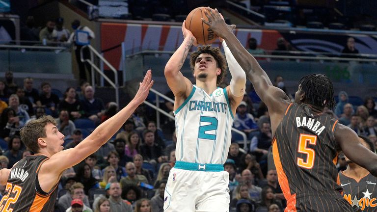 Charlotte Hornets guard LaMelo Ball goes up for a shot between Orlando Magic forward Franz Wagner and center Mo Bamba