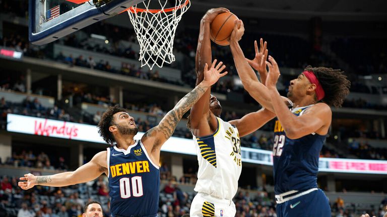 Indiana Pacers center Myles Turner, center, pulls in a rebound between Denver Nuggets guard Markus Howard, left, and forward Zeke Nnaji in the second half of an NBA basketball game Wednesday, Nov. 10, 2021, in Denver. (AP Photo/David Zalubowski)