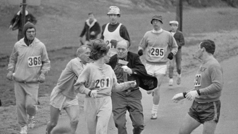 The rule that no women shall run in the Boston Athletic Association (BAA) Marathon is being put to a very real test in this photo. Trainer Jack Semple (in street clothes) enters the field of runners to try to pull Kathy Switzer (261) out of the race. Male runners move in to form protective curtain around the female track hopeful, until the protesting trainer is finally wedged out of the race, and the lady is allowed to finish the marathon.