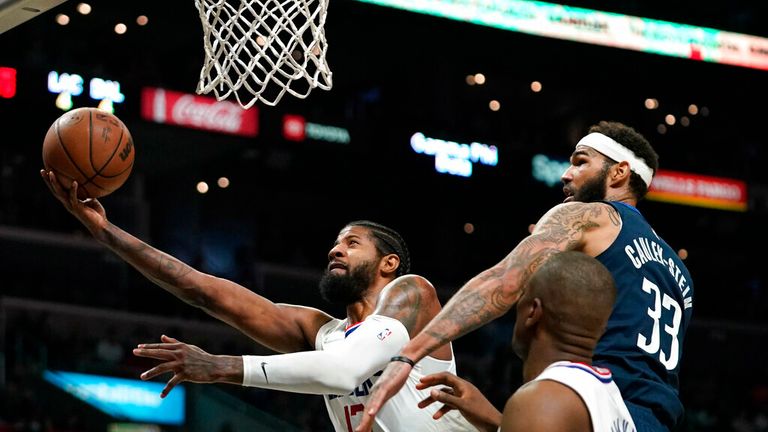 Los Angeles Clippers guard Paul George, left, shoots as Dallas Mavericks center Willie Cauley-Stein, right, defends and center Serge Ibaka watches during the second half of an NBA basketball game Sunday, Nov. 21, 2021, in Los Angeles. (AP Photo/Mark J. Terrill)