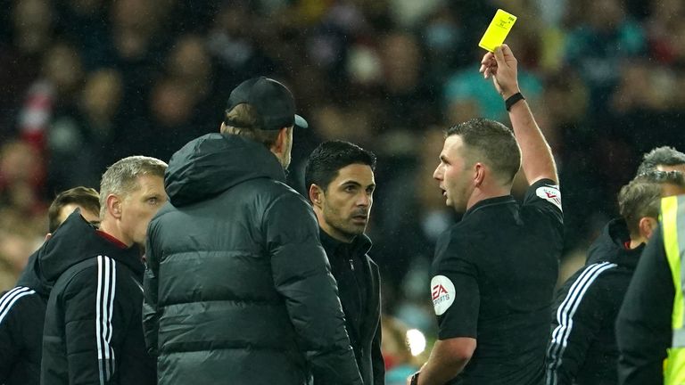 Mikel Arteta and Jurgen Klopp are both shown a yellow card by referee Michael Oliver following a clash on the sideline (AP)