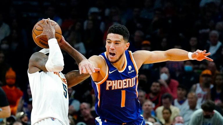 Phoenix Suns guard Devin Booker (1) is unable to steal the ball from Denver Nuggets forward Will Barton (5) during the second half of an NBA basketball game Sunday, Nov. 21, 2021, in Phoenix. The Suns won 126-97. (AP Photo/Ross D. Franklin)