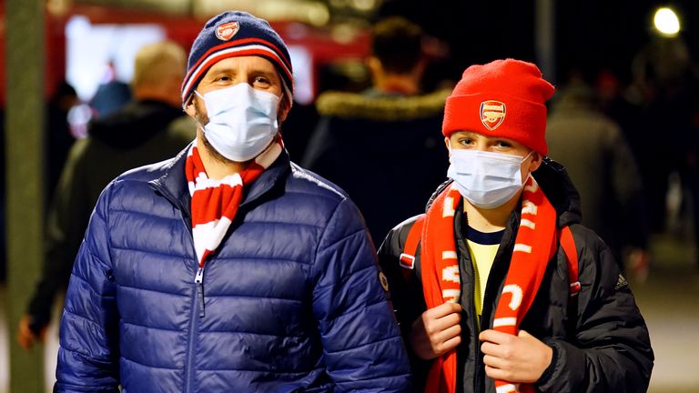 Two Arsenal fans wear face coverings ahead of their game with Leeds at Elland Road