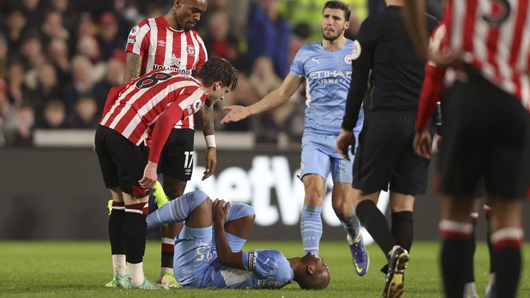 Fernandinho tient sa jambe alors qu'Ivan Toney lui fait face