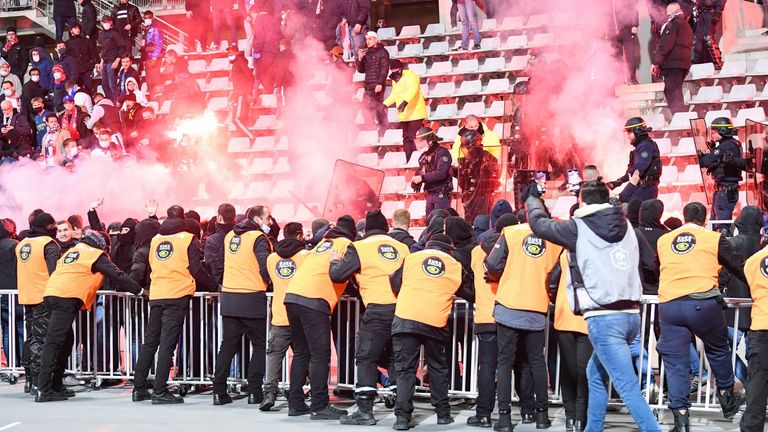 French anti-riot police officers intervene in the stand as supporters light flares at half-time during the French Cup game between Paris FC and Lyon