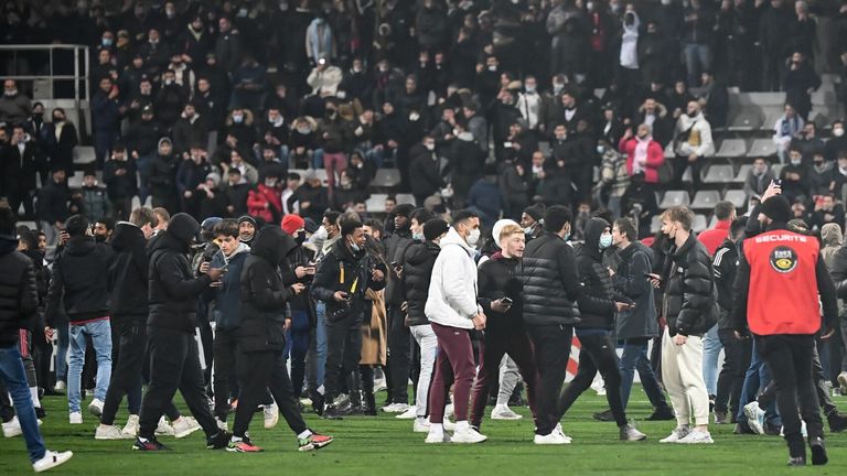 Supporters walk on the pitch at half-time during the French Cup round of 64 football match between Paris FC and Olympique Lyonnais