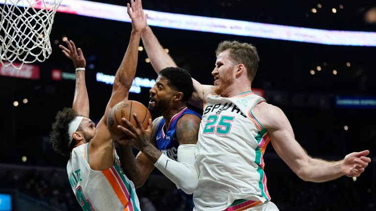 San Antonio Spurs guard Derrick White (4) and center Jakob Poeltl (25) defend against Los Angeles Clippers guard Paul George (13) during the second half of an NBA basketball game in Los Angeles, Monday, Dec. 20, 2021. 