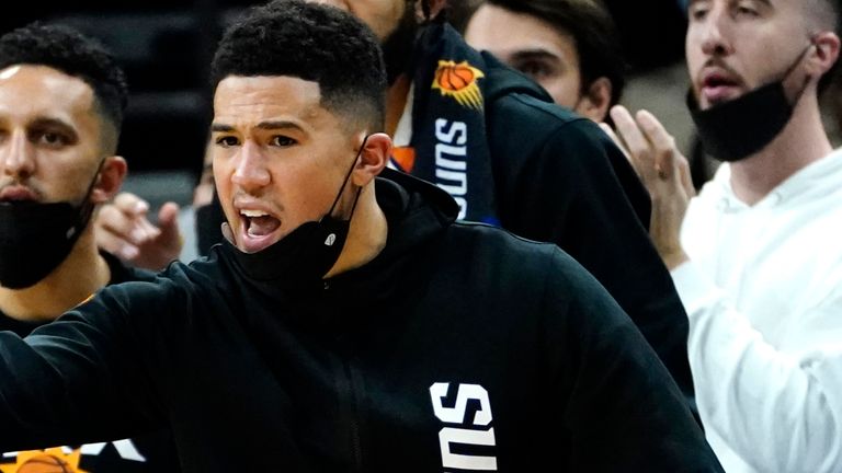 Devin Booker cheers on from the sidelines against the Golden State Warriors after going off injured